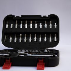 Open black case with red catches holding two rows of screwdriver bits and a row of small sockets, on grey