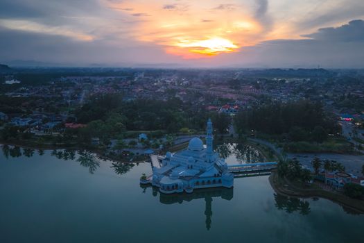 A mesmerizing aerial view of the floating mosque in Malaysia during sunset, surrounded by a serene landscape.