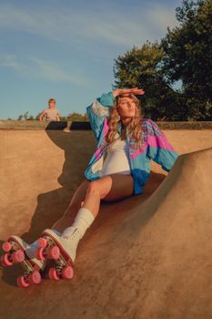 A woman relaxes in a skate park, wearing colorful roller skates under the summer sun.
