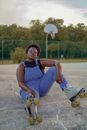 Self Confident Woman Sitting on Ground with Roller Skates on Feet
