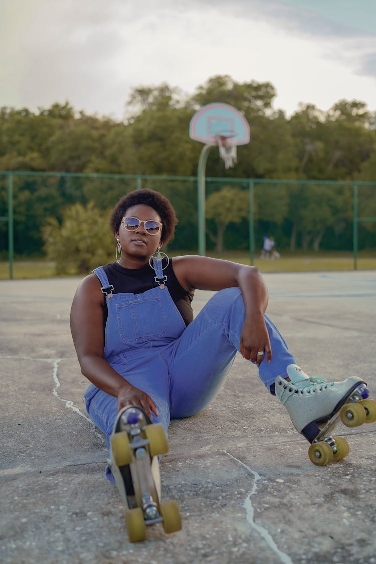 Self Confident Woman Sitting On Ground With Roller Skates On Feet