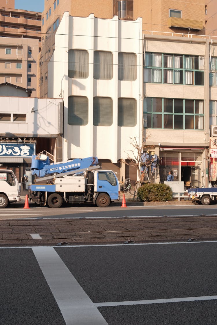 A Blue And White Truck Near Buildings