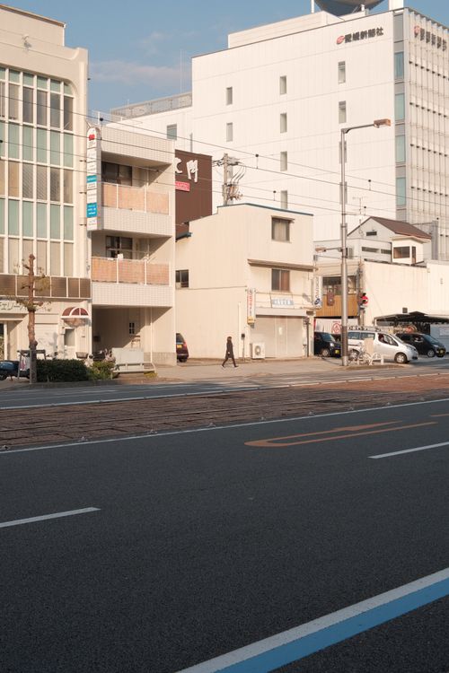 Free Street scene with modern architecture, vehicles, and a single pedestrian. Stock Photo