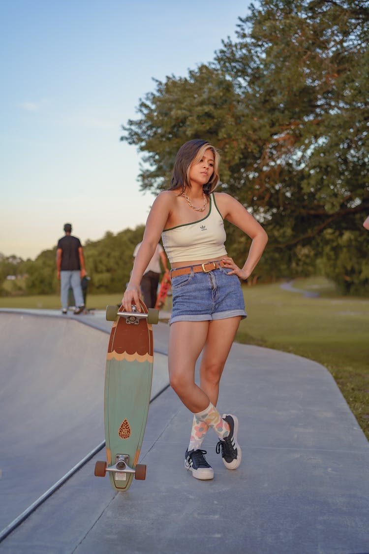 Woman With A Skateboard Posing With Her Hand On Her Waist