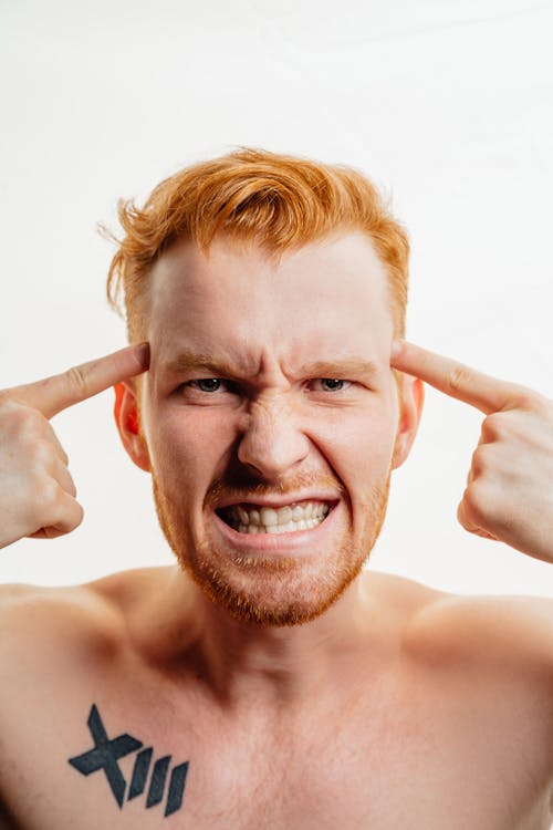 Free Redhead Man Clenching His Teeth and Pointing to His Temples Stock Photo