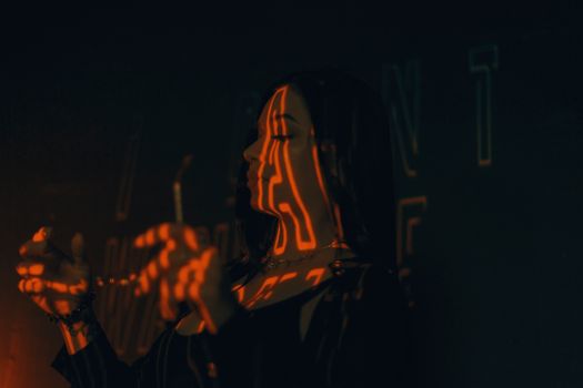 Artistic photo of a woman with orange light patterns, creating a mysterious atmosphere.