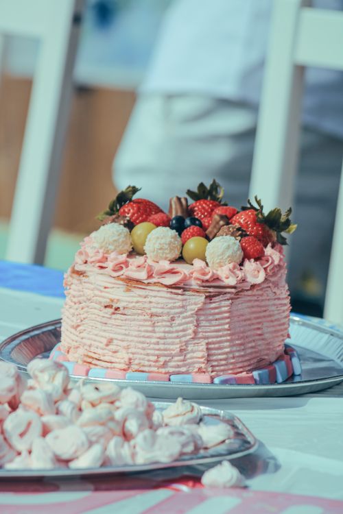 Free A pink layered cake topped with fresh berries and fruits, perfect for celebrations. Stock Photo