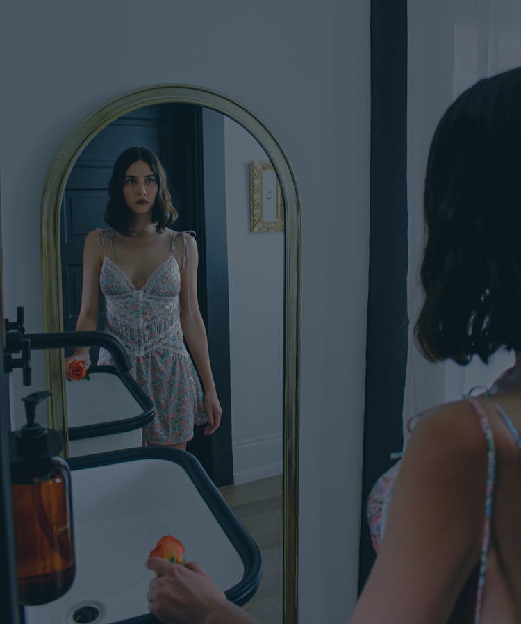 Woman In A Dress Looking At A Mirror