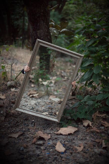 A mystical scene with a mirror reflecting forest foliage, hands mysteriously holding it.