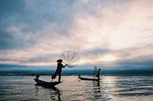 Silhouettes of Fishermen on Boats with Fish Nets