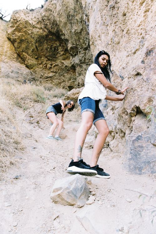 Free Two women engage in adventurous rock climbing on a rugged cliff under bright summer sky. Stock Photo