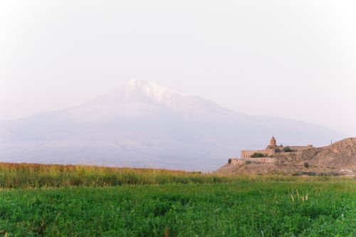 Free A picturesque landscape featuring a distant mountain and an ancient fort amidst lush fields. Stock Photo