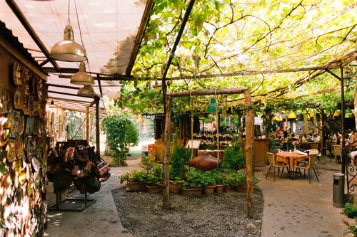 Free Beautiful outdoor cafe with lush greenery, rustic decor, and cozy ambience for dining and relaxation. Stock Photo