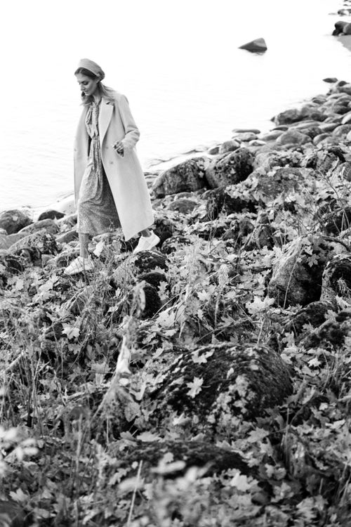 Free Fashionable woman in coat walking on rocky shore during fall, black and white photo. Stock Photo