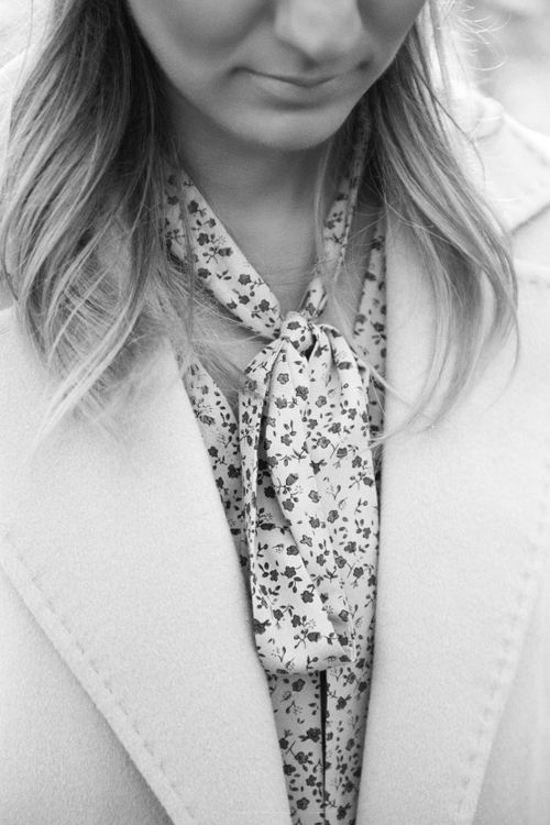 Free Black and white portrait of a woman wearing a floral blouse and coat, looking down. Stock Photo
