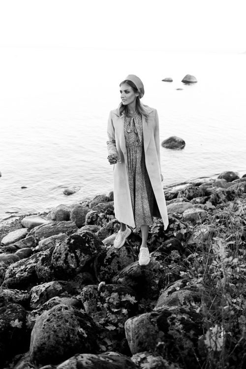 Free Black and white photo of a stylish woman on a rocky shore wearing a coat and beret. Stock Photo
