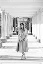 Black and White Photo of a Woman Standing Outdoors under a Colonnade