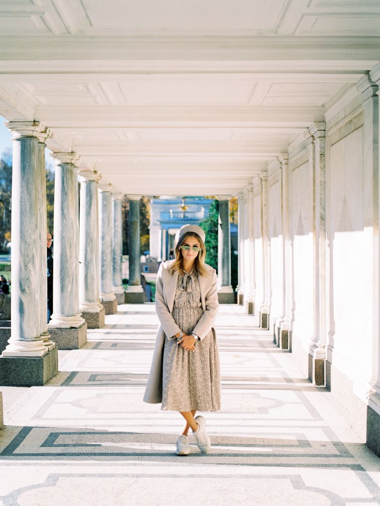 Woman Fashion Model Standing In Middle Of Colonnade 