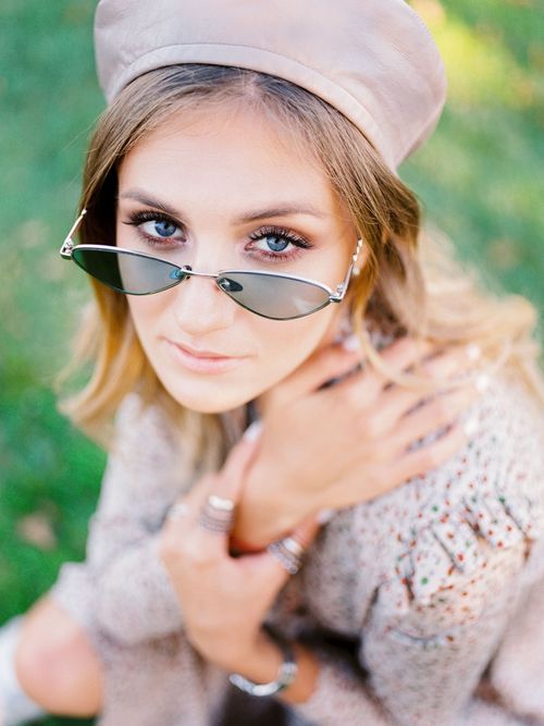 Free Portrait of a fashionable woman wearing sunglasses and a beret in a park setting, looking up thoughtfully. Stock Photo
