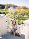 Woman Crouching at Classic Balustrade with Autumnal Park in Background