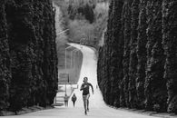 Black and White Picture of a Woman Running along an Alley Lined with Trees
