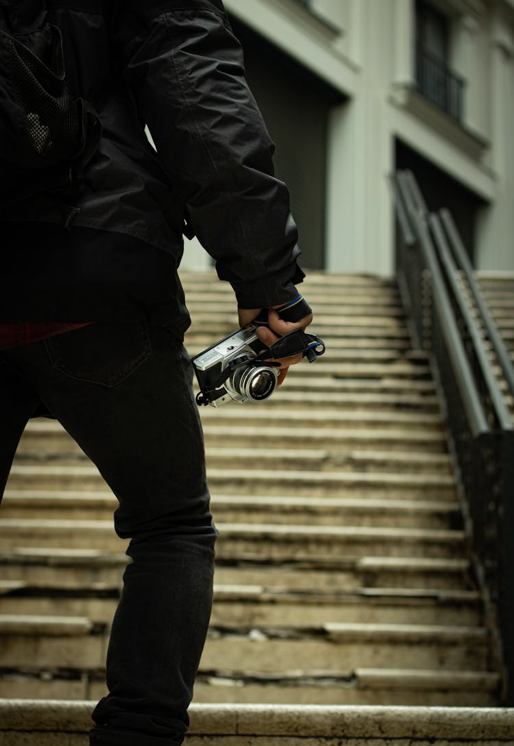 Man Holding A Camera While Walking Up The Stairs