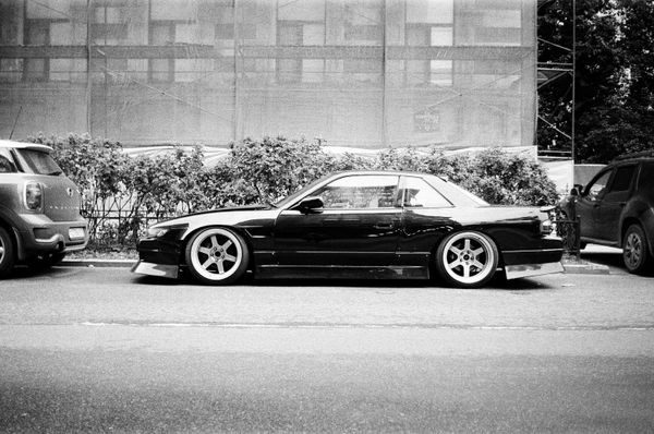 Lowered coupe on spoked wheels, side view in black and white
