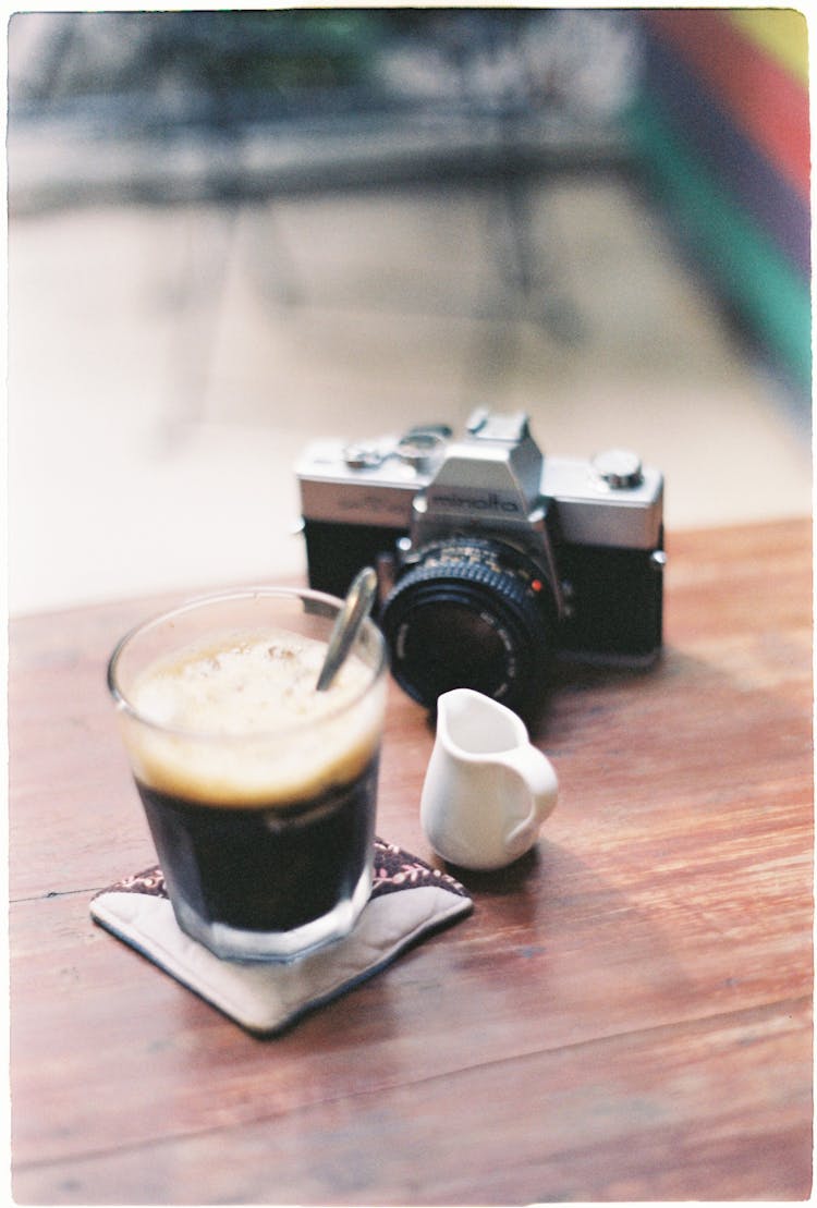 Close-Up Shot Of A Camera Beside A Glass Of Drink