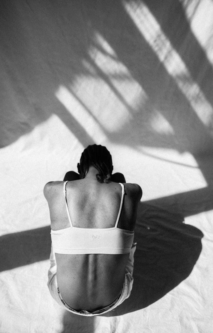 Black And White Picture Of The Back Of A Sitting Woman Bending