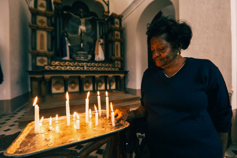 African American woman lighting candles in a serene church setting, capturing a moment of prayer and contemplation.