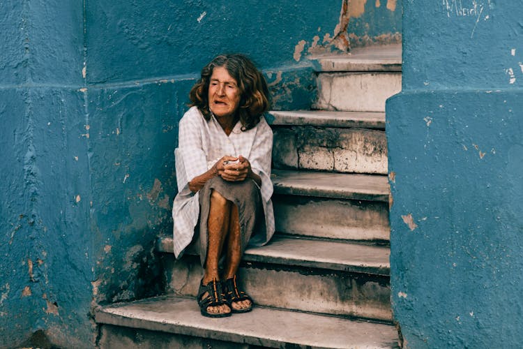 An Elderly Woman Sitting On The Stairs