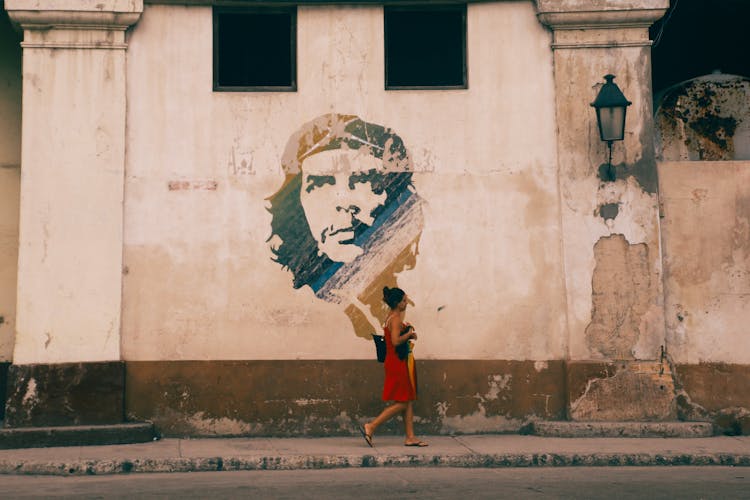 Woman Passing By A Building With A Mural Of Ernesto Che Guevara In Havana, Cuba