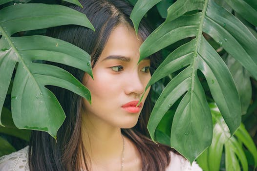 Captivating portrait of a woman surrounded by large green leaves, showcasing natural beauty and elegance.