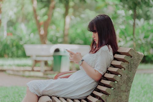 Woman Wearing White Dress Sitting on Bench