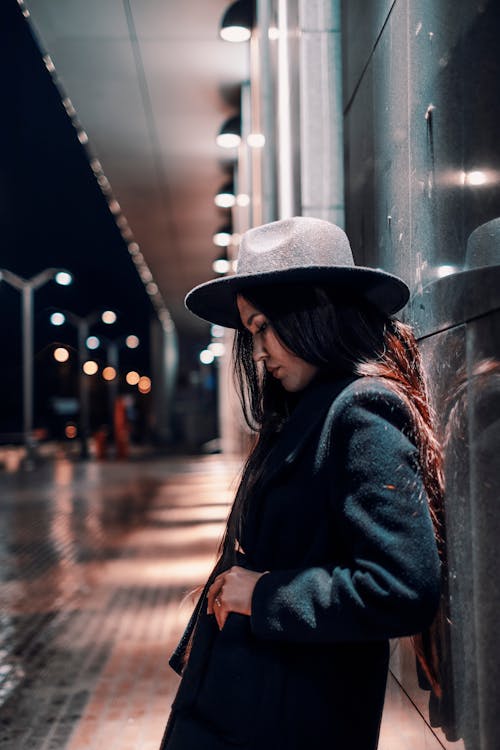 A Woman in Black Coat Leaning on the Wall