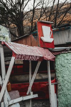 A vintage coffee shop facade with a rustic, weathered sign in an autumn setting. Outdoor scene.