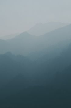 A serene, foggy mountain landscape with layers of mist at dawn, capturing nature's tranquility.