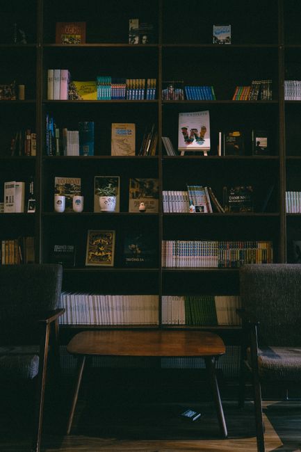 A warm and inviting library room featuring bookshelves, armchairs, and a wooden table.
