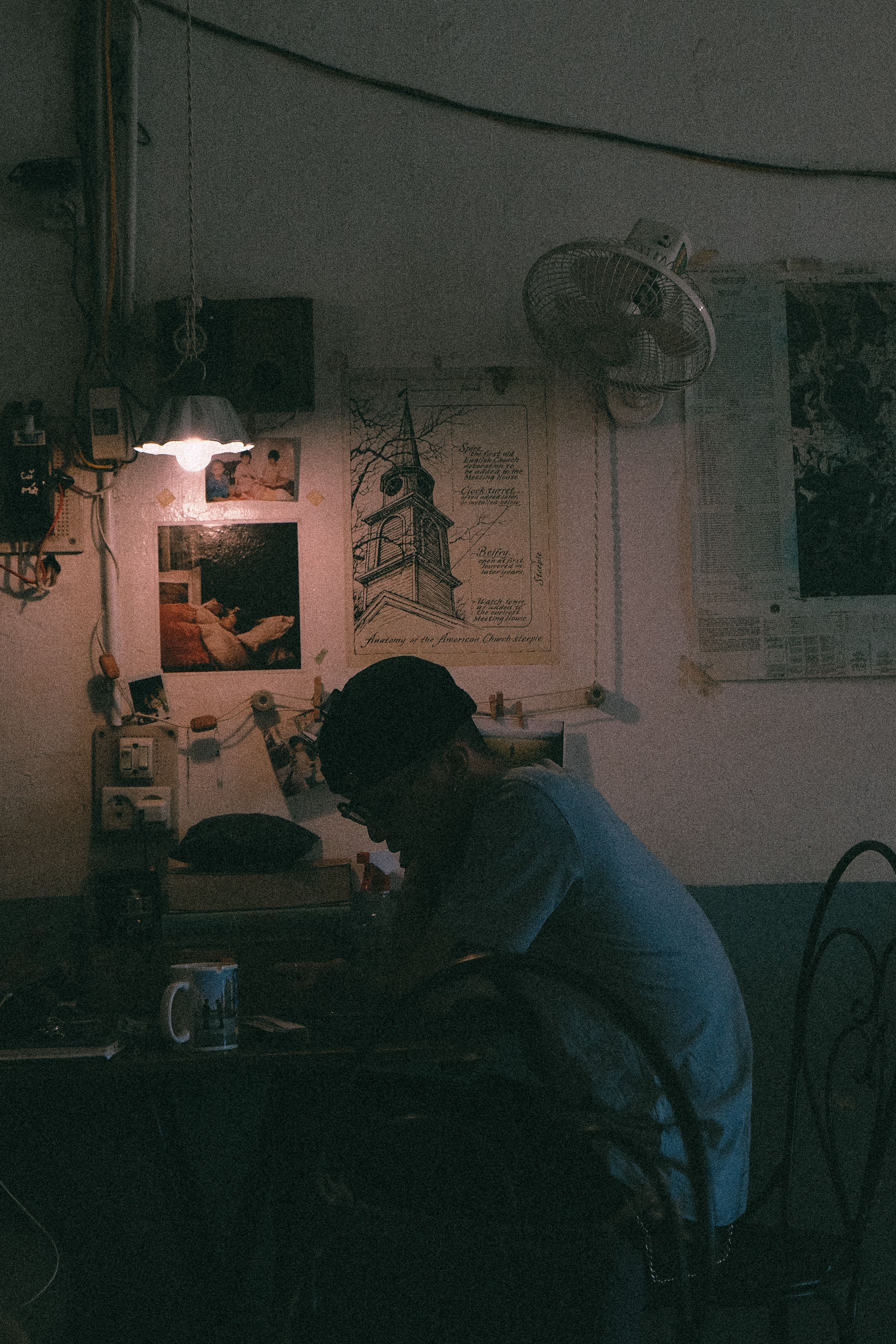 Moody indoor scene featuring a man sitting at a desk surrounded by art and a warm atmosphere.