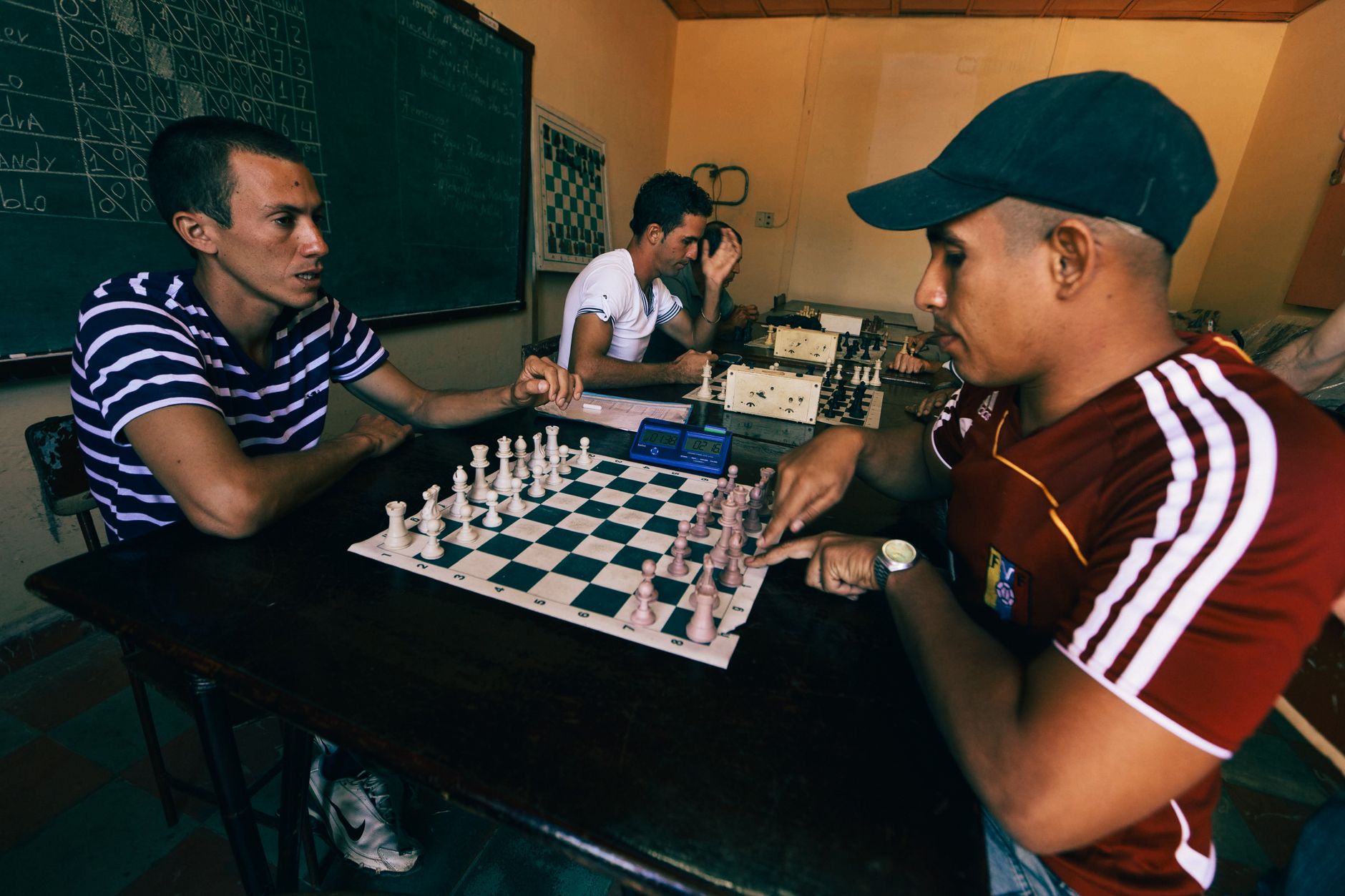 Young men engaged in a competitive indoor chess match, displaying focus and strategy.