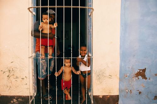 Free A family of four shares joyful moments at a doorway, emphasizing togetherness. Stock Photo