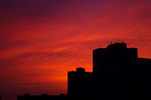 Free Dramatic silhouette of buildings against a vibrant red sunset sky. Stock Photo