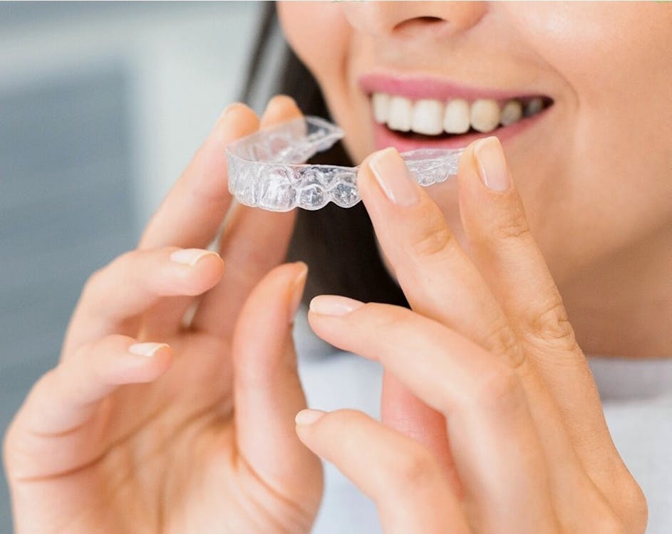 A photo showing a woman holding an Invisalign piece.