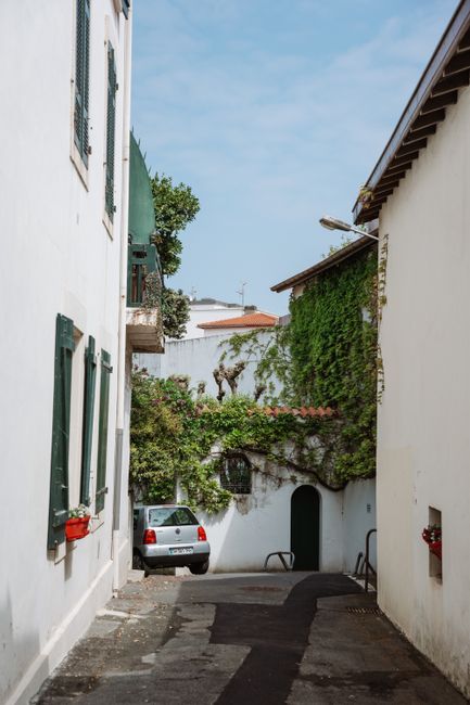 Peaceful narrow alley in Biarritz, France, featuring scenic buildings and a parked car.