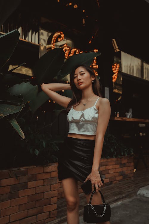 Woman in White Tank Top and Black Skirt Holding a Bag