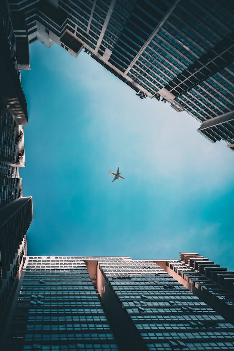 Worm's Eye View Shot Of An Airplane Flying Under Blue Sky