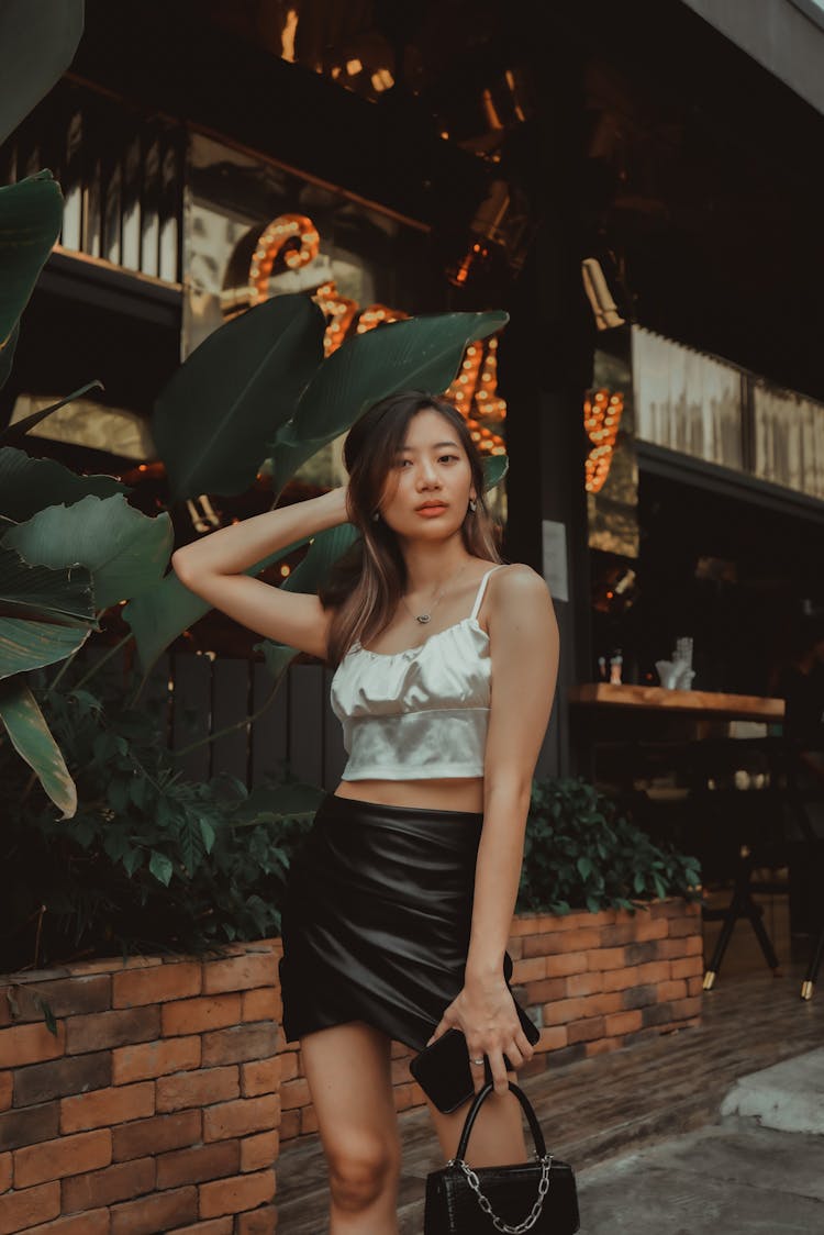 A Girl In A Black Skirt Posing With Her Hand On Her Head