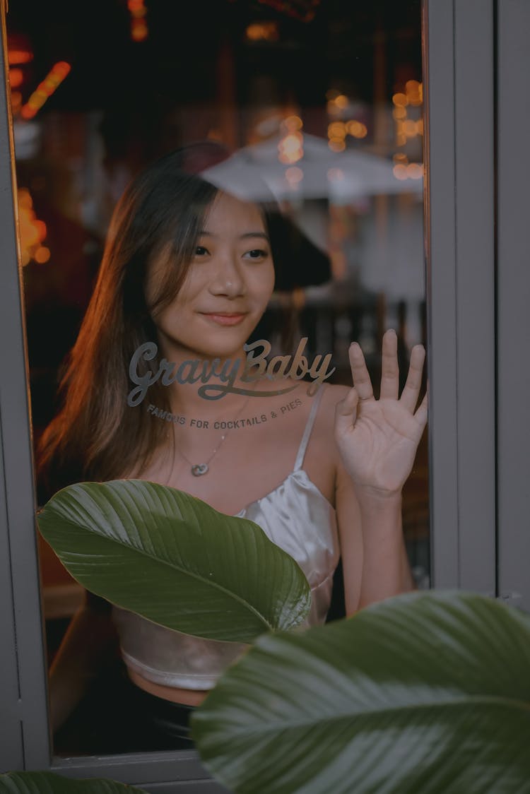 A Girl Looking Outside A Window