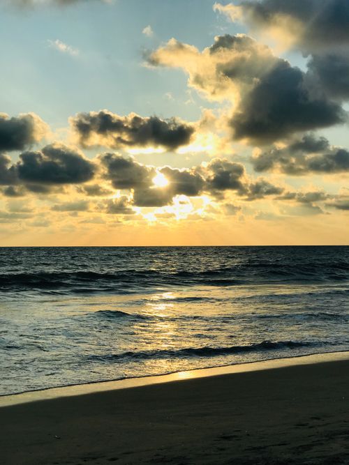 Free Stunning view of the ocean at sunset with dramatic clouds and gentle waves. Stock Photo
