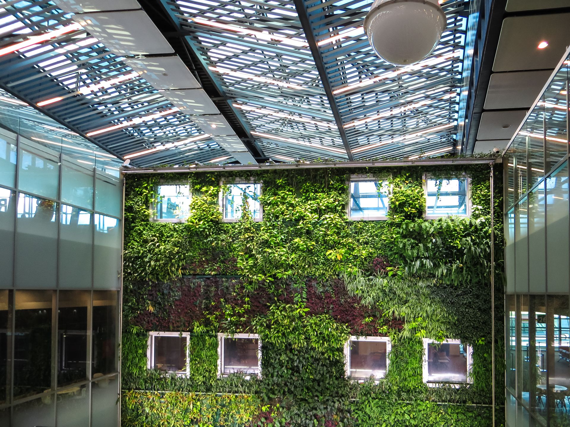 Contemporary indoor space featuring a lush vertical garden and a sleek glass roof, blending nature with architecture.